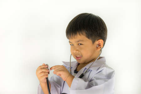Cute little boy in doctor costume holding stethoscope and smiling at skethoscope, kid looking camera,の写真素材