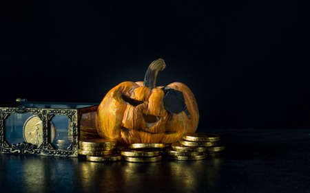 yellow pumpkin have black eye and gold coin on black background,の写真素材