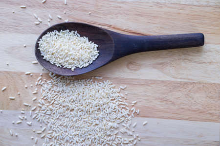 White rice in wooden ladle on wooden table, top view image, raw rice on wooden,の写真素材