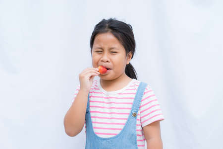 Portrait cute Asian girl eating red strawberry on white background, little girl eye sleeping eating strawberry,の写真素材