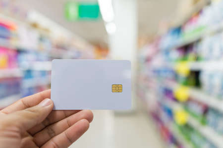 White card in hand on blurred Convenience Store background,の写真素材