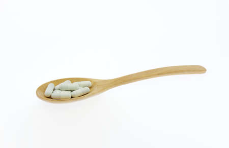 Capsule medicine in wooden ladle on white background,の写真素材