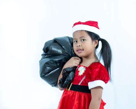 Cute Girl wearing Santa suit and holding black bag on white background,の写真素材