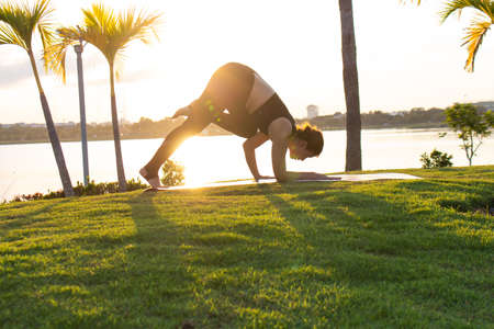 Women exercise to lift up the legs, lovely girl playing a yoga in the garden on light a sun...