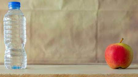Bottle water and red apple on the table with wall vintage background,の写真素材