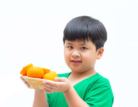 Little a boy holding orange in the basket on white background,の写真素材