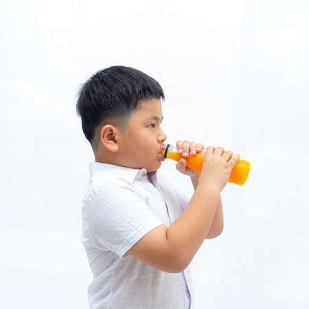 Asian cute a boy drinking orange juice water from bottle on white background,の写真素材