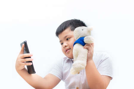 Cute a little boy selfie with bear on white background, boy holding a black smart phone,の写真素材