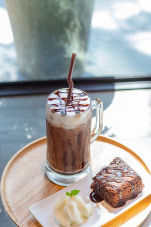 Ice coffee a late art in the glass on the table background, chockolate cake in wooden tray,の写真素材
