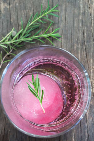 Raspberry flavour  ice in soda water decorated with rosemary place on wood stumpの写真素材