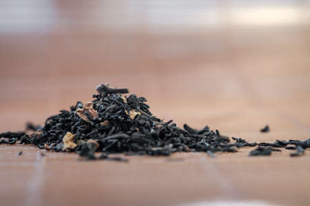 Heap of Dry tea leaves spread on light brown color backgroundの写真素材
