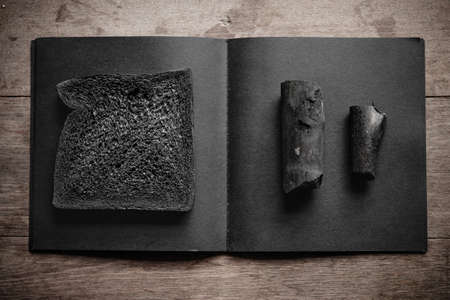 Charcoal breads loaf with charcoal placed on black notebook on wooden backgroundの写真素材