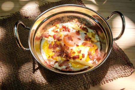 Indochina pan-fried egg topped with cheese and bacon place on linen weave in sunlightの写真素材