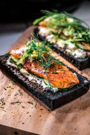 Charcoal Bread Salmon Sandwiches topped with cream cheese ,smoked salmon and dill placed on wooden...