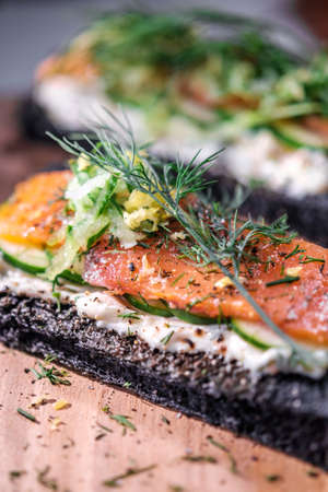 Charcoal Bread Salmon Sandwiches topped with cream cheese ,smoked salmon and dill placed on wooden boardの写真素材