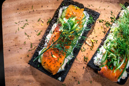 Charcoal Bread Salmon Sandwiches topped with cream cheese ,smoked salmon and dill placed on wooden...