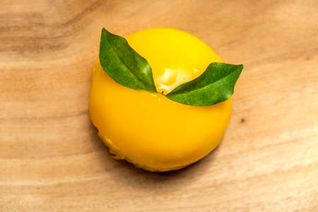 Orange cake topped with orange jam and leaf placed on wooden boardの写真素材