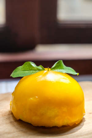 Orange cake topped with orange jam and leaf placed on wooden boardの写真素材