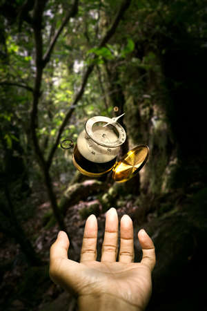 Surrealistic disintegrate Brass compass floating over hand in the middle of forestの写真素材