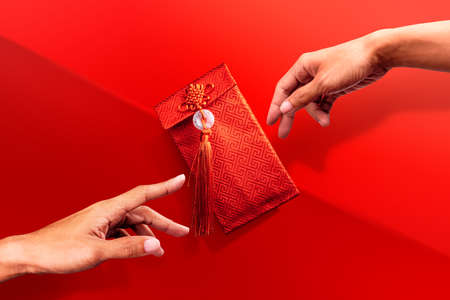 Hands reaching for Red Envelope in part of chinese traditionの写真素材