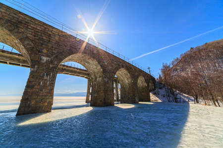 old arched railway bridge over river in winterの写真素材