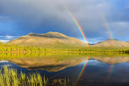 double rainbow over lake and mountainsの写真素材