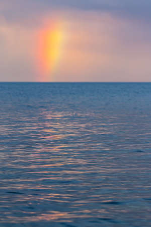 Rainbow over water at sunsetの写真素材