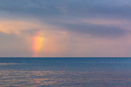 Rainbow over the water disappearing into the skyの写真素材