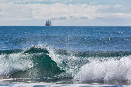 The wave rolls ashore on the background of the shipの写真素材