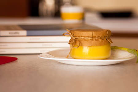 Little glass jar of sweet apricot jam on the white plate that on the tableの写真素材