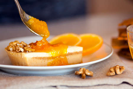 Tasty piece of cake spreaded with delicious orange jam and nuts for lunchの写真素材