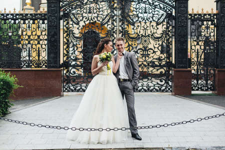 Happy beautiful newlyweds standing in front of the gates and smiling.の写真素材