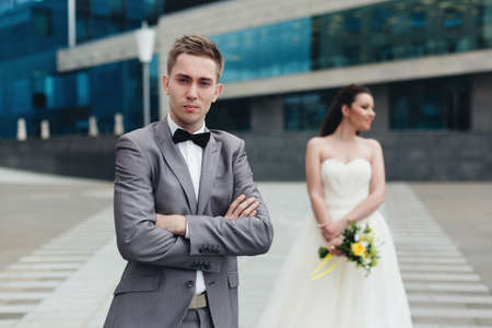 Smiling bride holding a bouquet and standing behind her groom.の写真素材