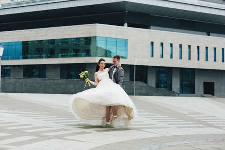 Smiling groom is holding his happy bride in front of the building.の写真素材