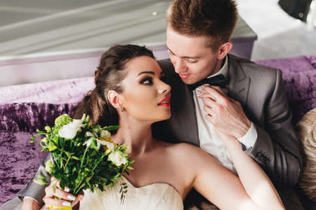 Smiling groom hugging and holding his beautiful bride's handの写真素材