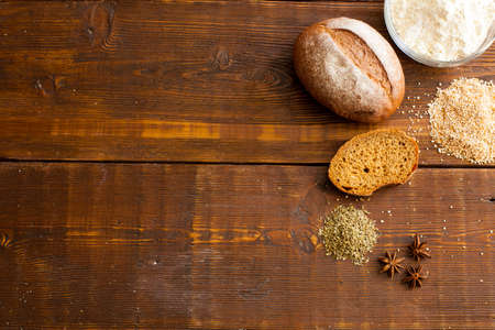 Fresh brown crispy bread with flour, loaf of bread and wheat grain on the wooden tableの写真素材