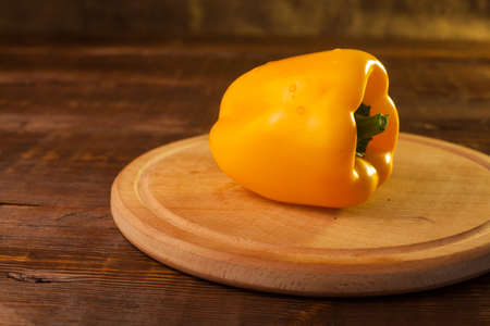 Yellow paprika is on the plank on the tableの写真素材