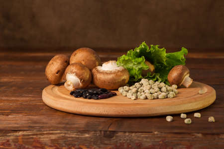 Mushrooms,  salad and grains are on the plank on the table