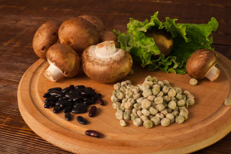 Mushrooms,  salad and grains are on the round plank on the wood tableの写真素材
