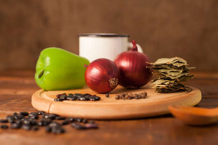 Green paprika, onion and grains are on the plank on the wood tableの写真素材