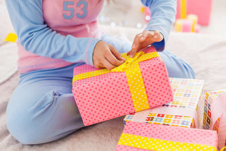 Young girl opening her New Year presents in bedroomの写真素材