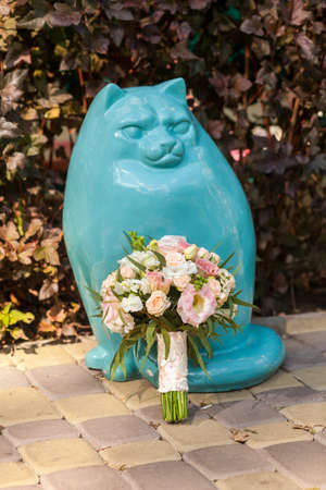Beauty wedding bouquet near the blue statue of catの写真素材
