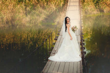 Woman bride in beauty  wedding dress standing on bridgeの写真素材