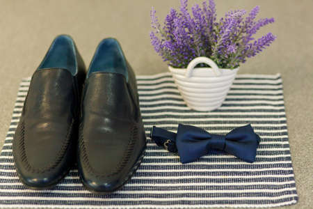 Elegant shoes and bow-tie near vase with lavender on tableclothの写真素材