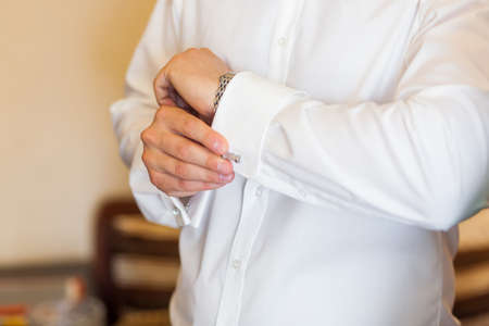 Bridegroom buttoning cuffs on his white wedding shirtの写真素材
