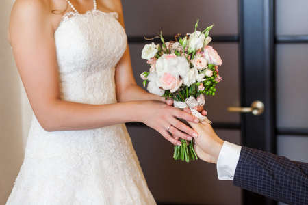 Groom giving elegant wedding bouquet to his brideの写真素材