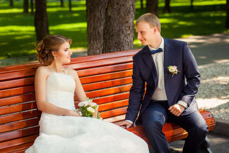 Wedding couple on old-fashioned bench in summer parkの写真素材