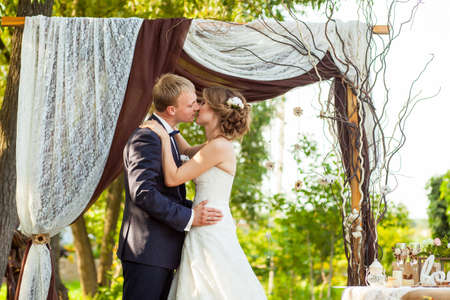 Wedding couple kissing under the decorative wedding archの写真素材