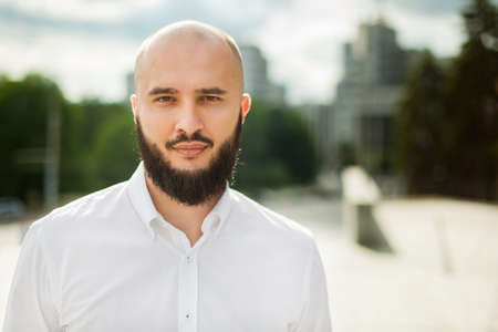 Businessman with beard in white shirt standing and looking in cameraの写真素材