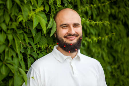 Portrait of funny smiling man with decoration in his beard